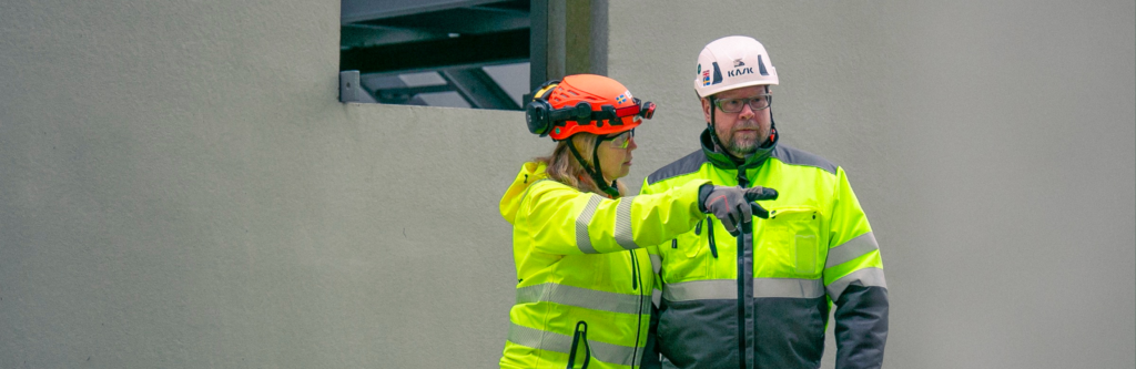 Två personer i varse- och skyddskläder på site.